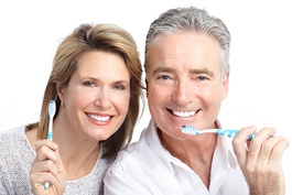 An older man and woman holding toothbrushes