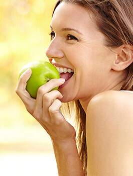 Jovial Woman biting green apple after preventive dentistry in Buckhead Atlanta