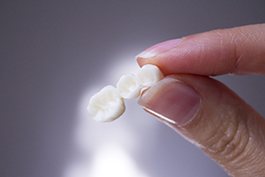 Fingers holding dental bridge