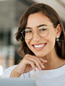 A young, smiling woman wearing rounded glasses