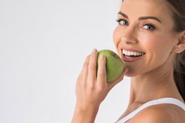 young woman biting into a green apple