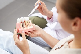 dentist showing a patient a model of a dental implant