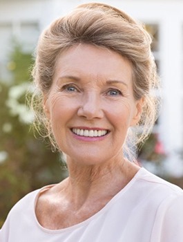 An older woman smiling outside.