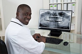 Male dentist looking at x-rays showing an impacted wisdom tooth