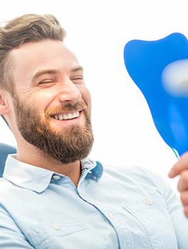 Man looking at his smile in mirror after tooth extraction in Buckhead Atlanta