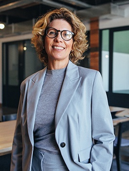 Middle-aged woman in glasses smiling after receiving tooth-colored fillings in Atlanta