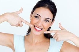 Young woman pointing to her smile tooth-colored fillings