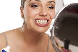 Woman looking at her smile while holding toothpaste