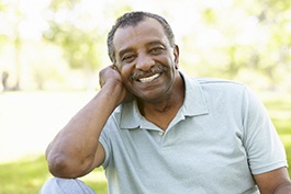 Man in grey polo smiling outside