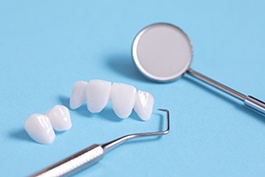 Different dental bridges with dental instruments and blue background