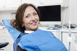 Woman in dental chair smiling with technology in the background