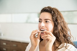 Closeup of woman placing Invisalign clear aligner in her mouth