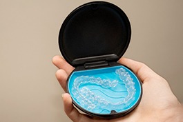 Closeup of patient holding clear aligners in Invisalign storage case