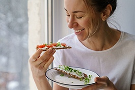 Woman smiling while eating healthy meal at home