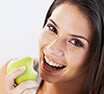 Buckhead Dental Services woman happily biting apple