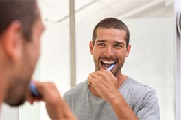 a person brushing their teeth while looking in a bathroom mirror