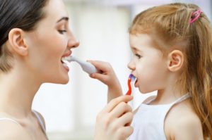 Mother and daughter brushing each other's teeth after seeing Buckhead dentist 