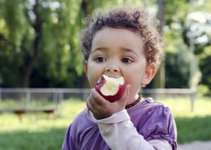 a child eating an apple while playing outside