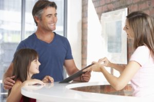 Father and dentist discuss children's dental insurance coverage