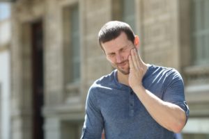 : a man experiencing facial pain due to a dental emergency