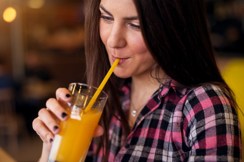 Woman drinking orange beverage with a straw