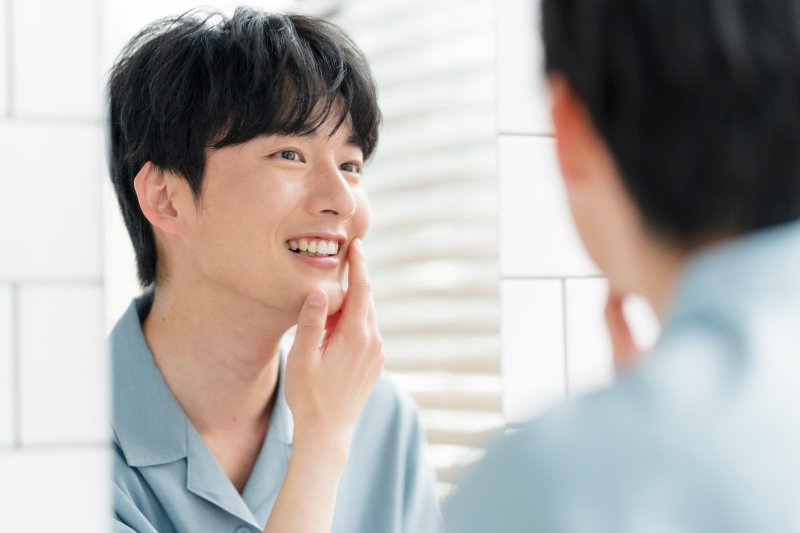 a man smiling and touching his youthful face