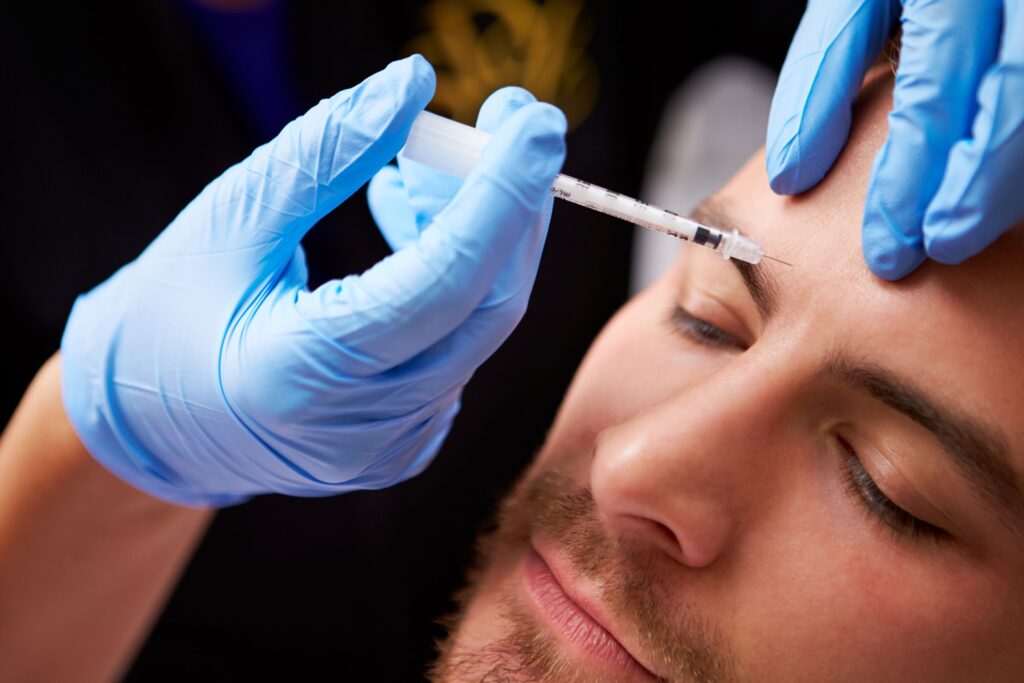 Closeup of gloved hands injecting Botox into man's eyebrow area